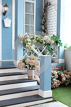 House entrance staircase at home decorated for holiday. Wooden porch of house with different flowers. Terrace of summer house