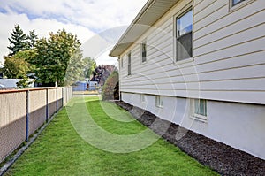 House exterior. View of side wall and green grass.
