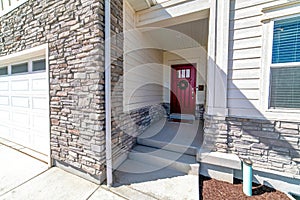 House facade with vibrant red front door attached garage and stone brick wall