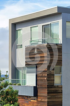 House facade with wooden frame and moddern beige stucco house frame with windows and flat roof