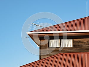 House with first floor under metal hip roof, cedar weatherboards