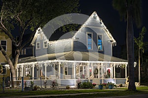 House front yard with big porch brightly illuminated with christmas decorations. Outside decor of florida family home