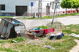 House furniture dumped in the garbage on the street in the city near metal dumpster junk can