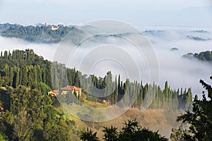 House in green and foggy Tuscany hillside