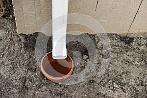 House gutter. Rainwater drainage system concept. White pipe for rainwater from roof on building and drain pipe in ground