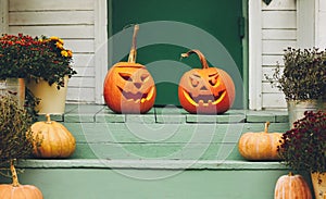 House with halloween orange pumpkin decoration, jack o lanterns with spooky faces on porch