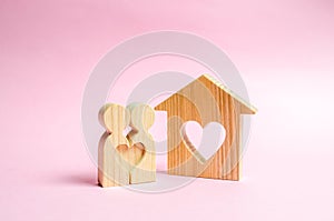 A house with a heart stands between a pair of lovers. The concept of finding a love nest. Mortgage, purchase credit.