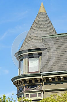 House or home with spire or turrent structure with windows and gable roofs with green wooden tiles of timber midday sun