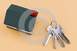 House and house keys against a beige background, top view
