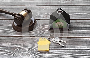 House, house keys with a key ring, judge hammer on a wooden background.