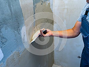 House improvement by worker. Hand with a spatula. Worker trowels putty on wall with finishing putty.