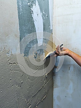 House improvement by worker. Hand with a spatula. Worker trowels putty on wall with finishing putty.