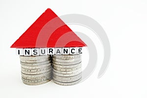 House insurance concept with small house from coins and wooden piece on white background