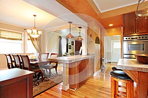 House interior with open wall design. View of dining table set and kitchen room.