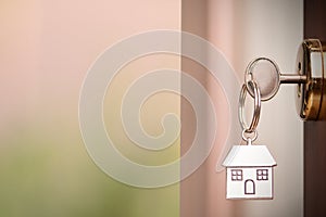House key in the door. Close House key on a house shaped silver keyring in the lock of a entrance brown door