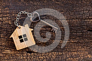 House key in heart shape with home keyring on old wood background