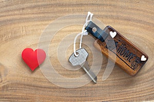 House key in heart shape with home keyring on old wood background decorated with mini heart