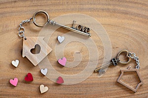 House key in heart shape with home keyring on old wood background decorated with mini heart