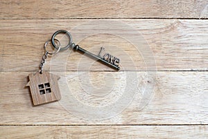 House key in heart shape with home keyring on white wood background