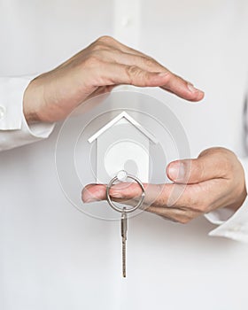 House key in home insurance broker agent`s hand protection or in salesman person giving to buyer customer