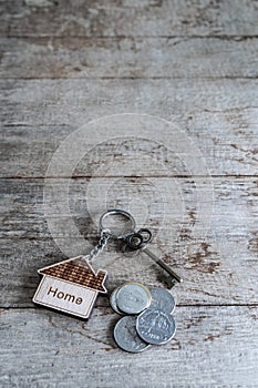 House key with home keyring with coin pile on rusty wood background