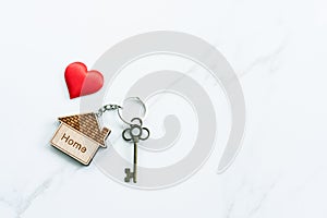 House key with home keyring decorated with mini heart on rusty wood background