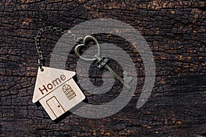 House key with home keyring decorated with mini heart on rusty wood background