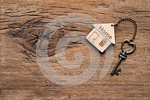 House key with home keyring decorated with mini heart on rusty wood background