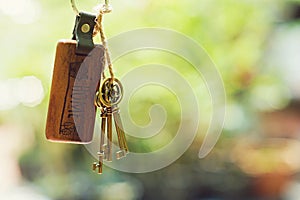 House key with home keyring in keyhole with blur green garden background, property concept