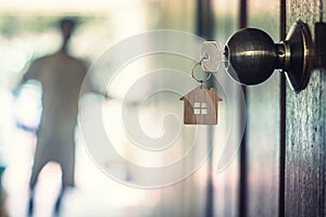 House key with home keyring in keyhole on wood door