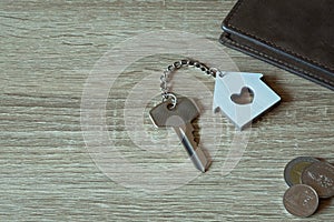 House key with home keyring and wallet on wood table