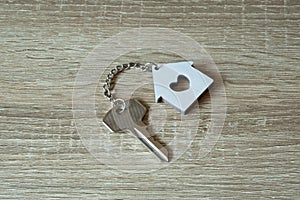 House key with home keyring and wallet on wood table