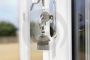 House key on a house shaped silver keyring in the lock of a door