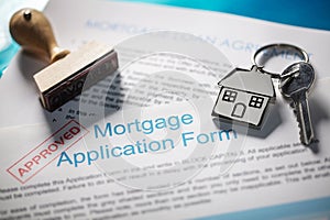 House key on keyring with mortgage application form and loan agreement
