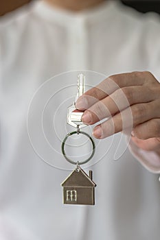 House key in real estate sale person, landlord or home Insurance broker agent`s hand giving to buyer customer for new family owner