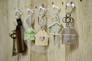 House key with wooden home keyring hanging on wood board background, property concept, copy space