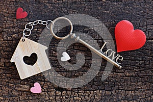 House keyring and love shape key on vintage wooden table. Decorated with mini heart as sweet gift for lover or family member. Home