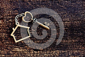 House keyring with vintage heart shape on old wooden table. Welcome new home, home sweet home concept. Copy space