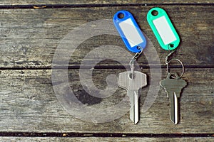 House keys with color tag keyring with green garden background, property concept, copy space