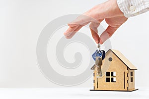 House keys in hand against a toy building on white