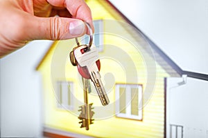 House keys in the hands against the background of the finished built yellow building