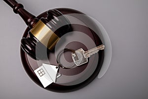 House keys and judge`s gavel on a gray background