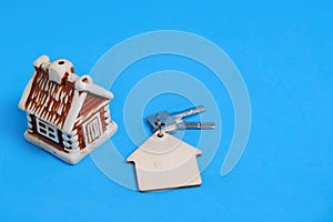 House and keys with keychain on blue background, sale and purchase of an apartment