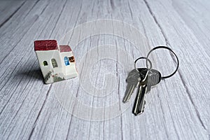 House keys and a small model of house in the wooden background, real estate concept