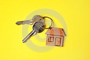 House keys with trinket on color background