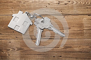 House keys with trinket on wooden background