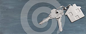 House keys with trinket on wooden background