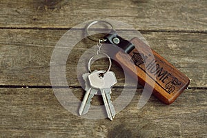 House keys with wooden home keying on wood table, copy space, property concept