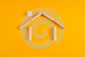 House made out of wooden blocks on yellow background. Home ownership and insurance