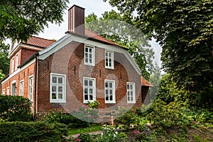 House made of red clincker bricks surrounded by green trees